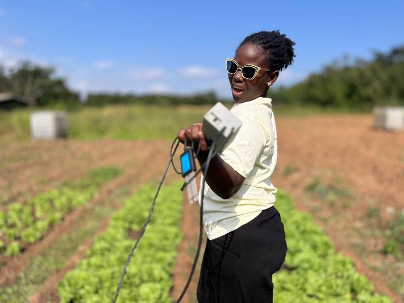 A SoilPulse team member holds up the reader and probe in a vegetable field